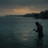 A lone fisherman standing in dark still water at dusk, waiting without a catch — a metaphor for the cold start problem in personalization